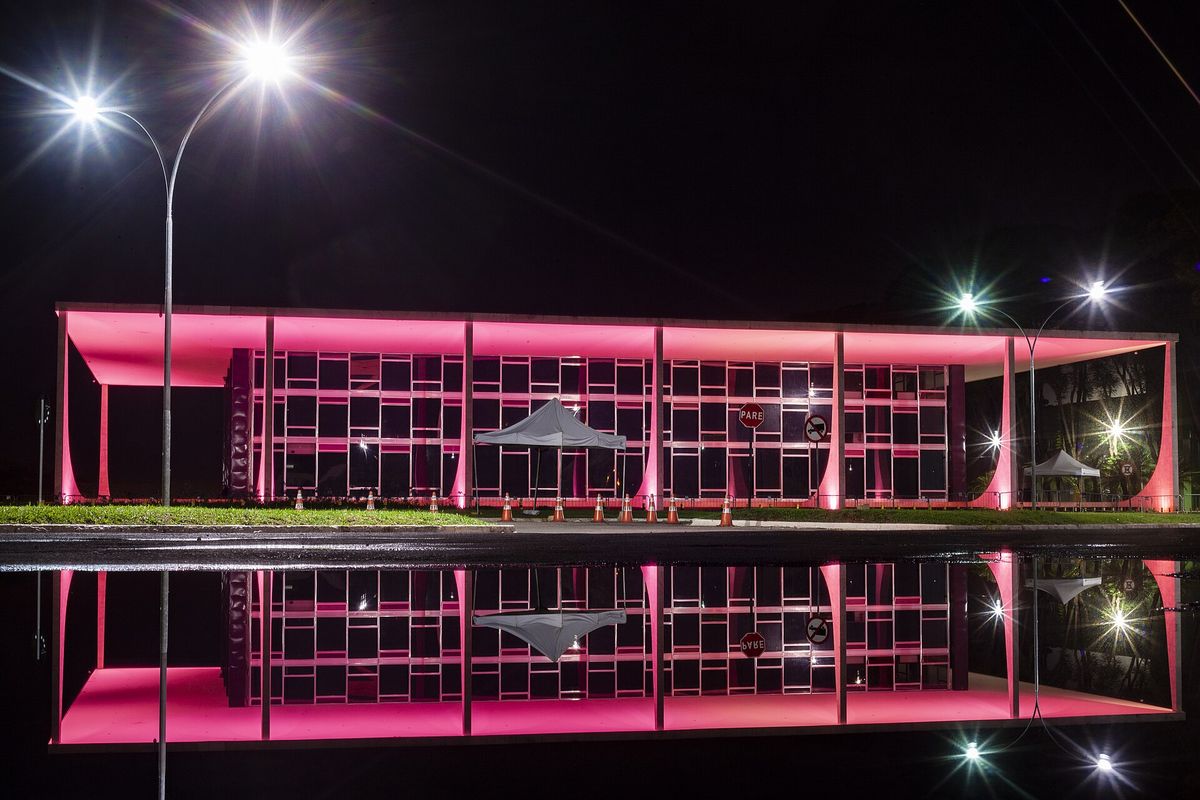 Supremo Tribunal Federal iluminado à noite, com reflexo no espelho d'água
